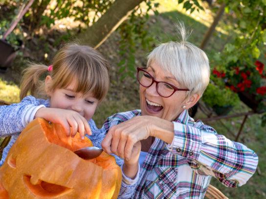 grandparent and grandchild carving jack-o-lantern